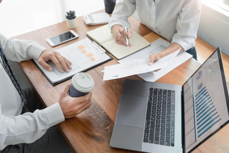 Two people having a business meeting with a laptop, documents, and coffee on a table.