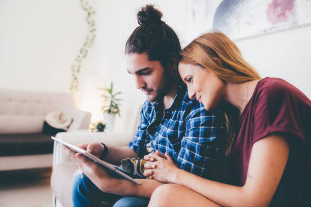 A couple reviews housing options on a tablet, highlighting the appeal of Dubai's real estate market.