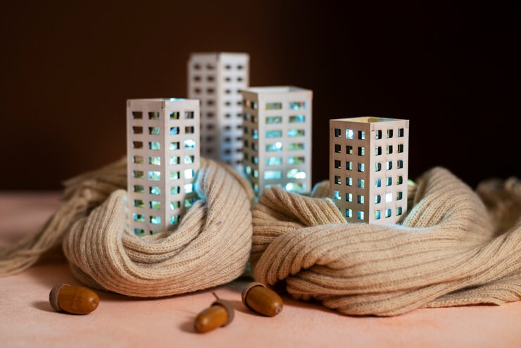 Lit miniature buildings wrapped in cozy knitted scarves with acorns scattered around.