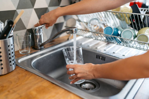 A person fills a glass with water from an efficient faucet at Binghatti Hills to conserve water.